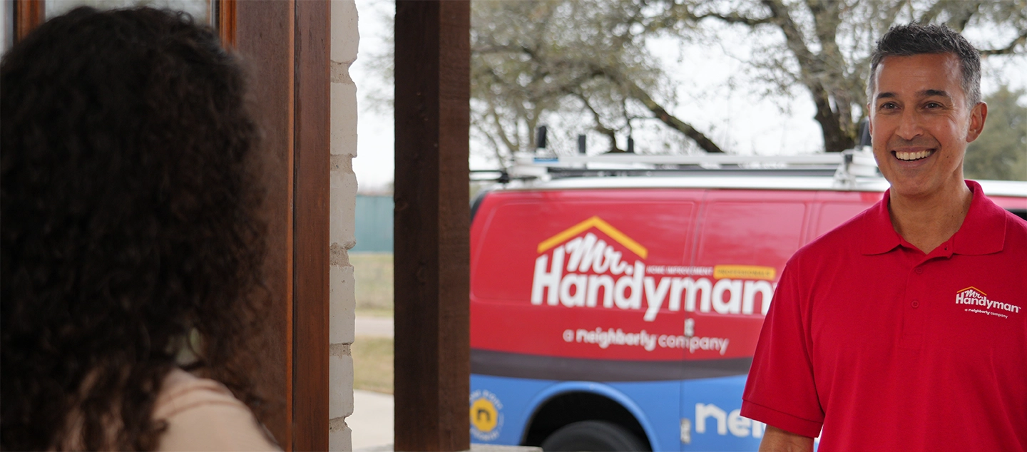 A Mr. Handyman service professional standing next to a service vehicle.