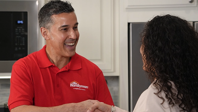 A Mr. Handyman service professional shaking hands with a customer.