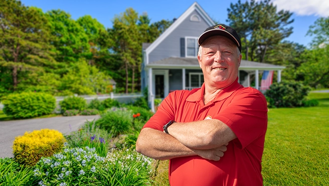 Mr. Handyman representative standing with arms crossed in front of house.