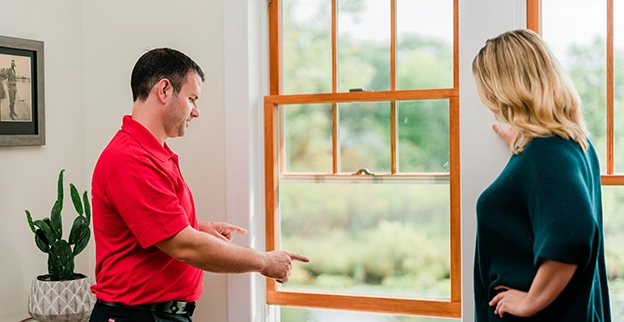 Mr. Handyman tech showing customer a window.