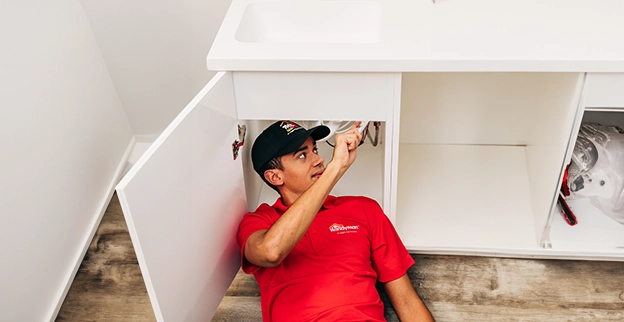Mr. Handyman worker repairing washbasin pipes.