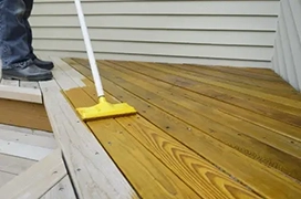 Person staining wood deck.