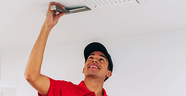 A picture of person using a scraping knife on a ceiling.
