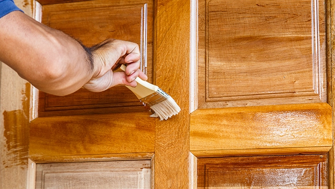 A picture of a person staining a door.