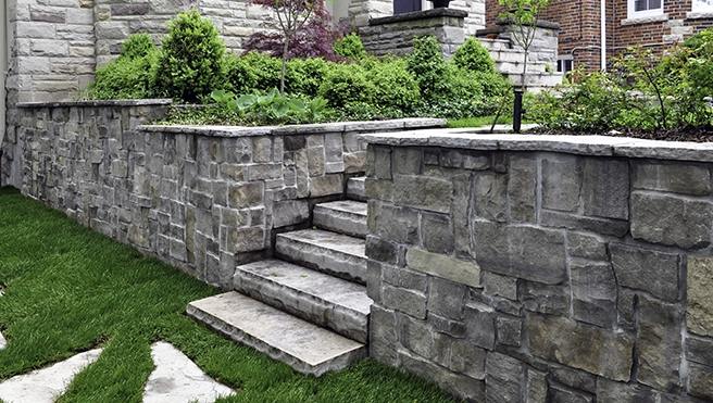 A picture of a stone wall and steps in a yard.