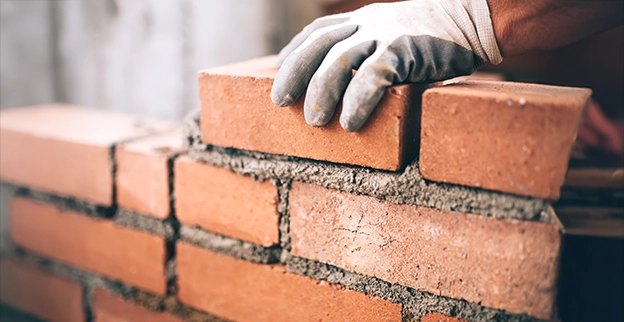 A picture of a bricklayer laying bricks.
