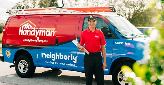 Mr. Handyman tech standing in front of a service van,