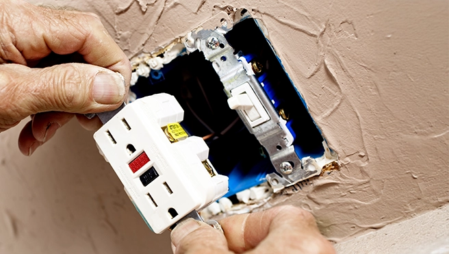 A picture of a GFCI-rated outlet being installed in a wall.