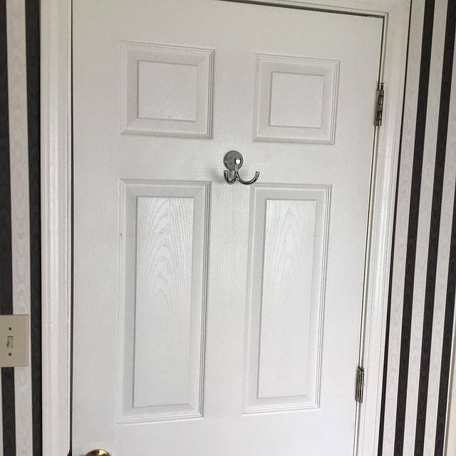 Coat/towel hanger on white door with back and white striped walls