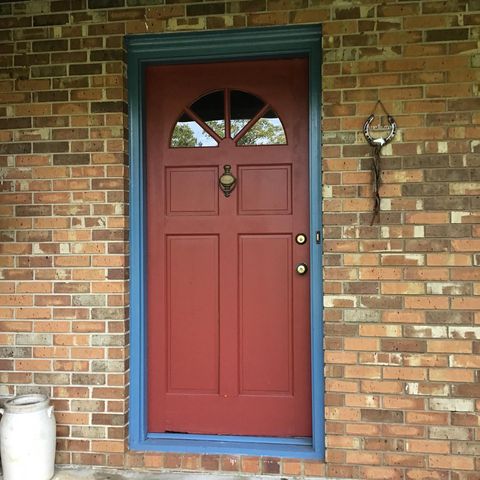New door installation with red door and painted blue trim surrounded by brick