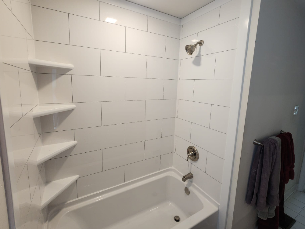 Clean white subway tile tub surround with built-in corner shelving and brushed nickel fixtures – Mr. Handyman of Lehigh Valley.