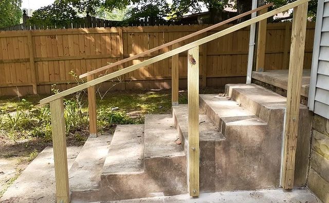 Wood railing and cement steps leading to a house