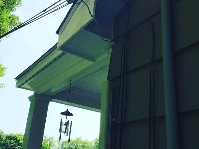 There are wind chimes on a house where cables connect to the house.