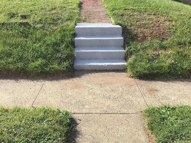 This is a set of steps in the yard by the sidewalk.
