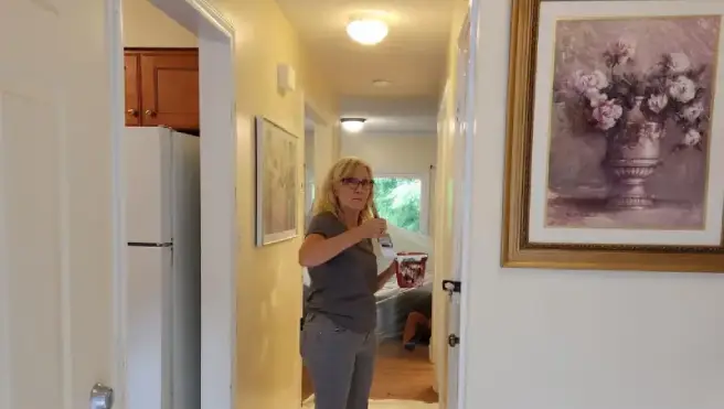 A Mr. Handyman technician painting the hallway of a home.