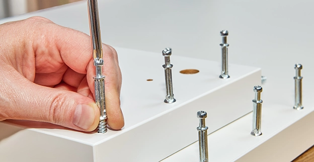 A hand using a screwdriver to tighten metal screws.