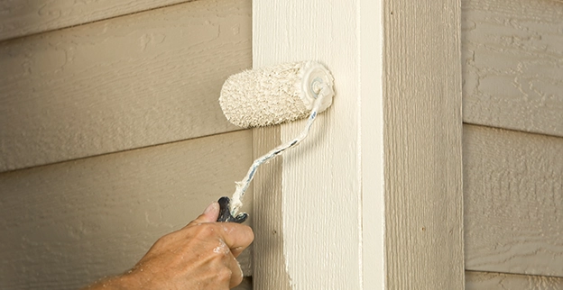 Employee painting wooden wall with brush.