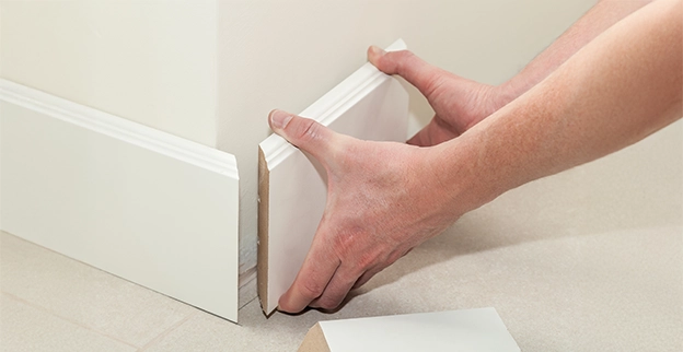 Hand holding a corner piece of a floor tile.