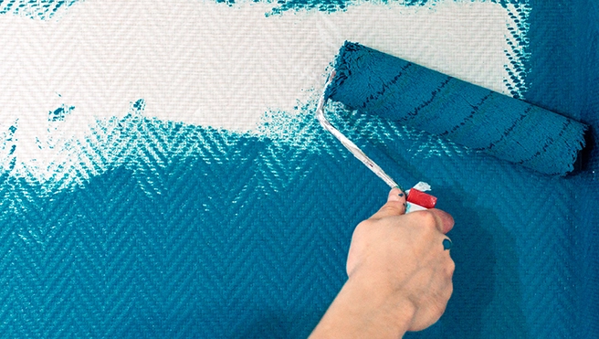 MRH employee painting wall with blue paint.