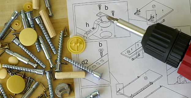 A collection of screws and wooden dowels scattered around assembly instructions.