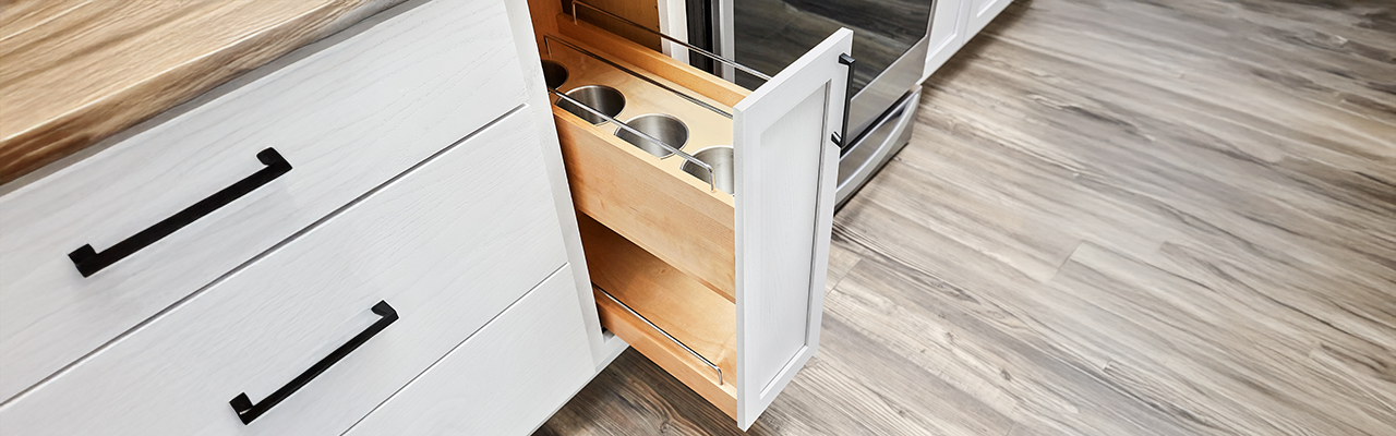 A wooden kitchen drawer partially open, revealing metal containers inside.