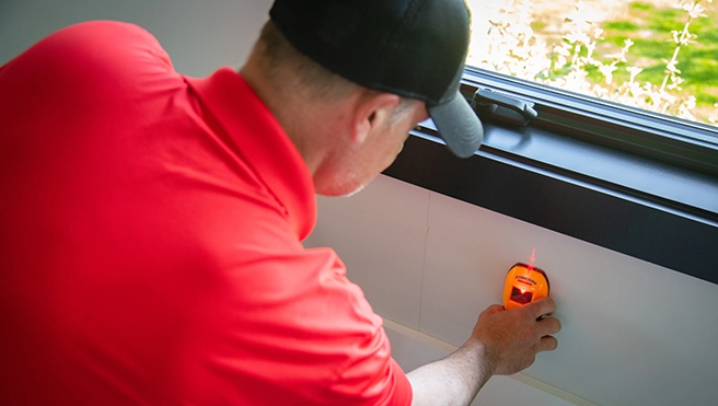 MRH technician using a stud finder to locate wall studs.