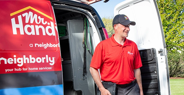 A handyman worker steps out of a Mr. Handyman van.