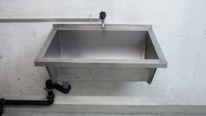 A water pipe connected to a washbasin in a washroom.