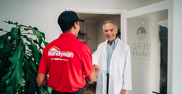 Mr handyman in a red shirt shakes hands with a man.