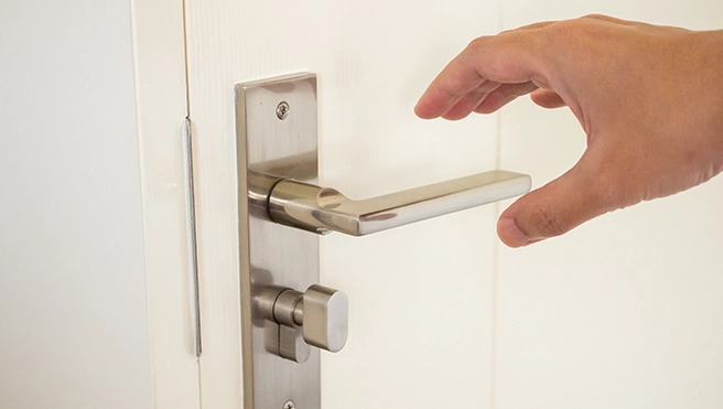 A hand reaching for a sleek stainless steel door handle.