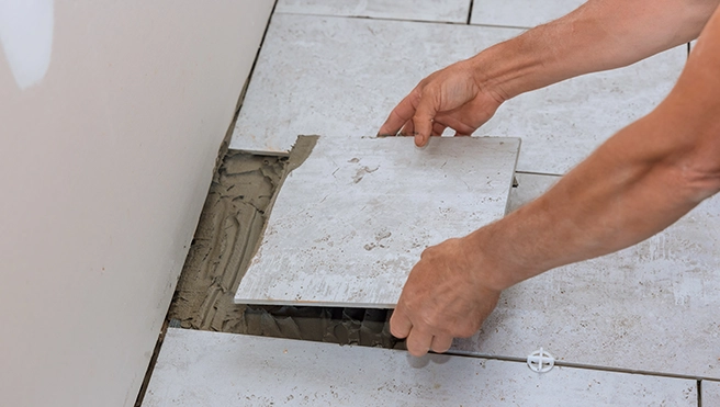 Handyman placing a tile to complete tile installation.