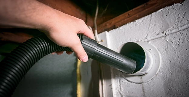 Service professional cleaning out a dryer vent exhaust.
