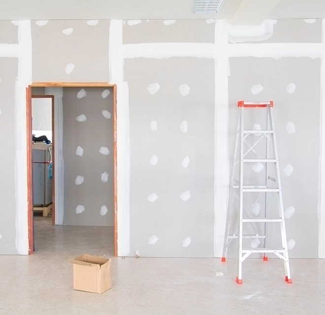 A partially renovated room with unfinished drywall featuring an open doorway to another space.