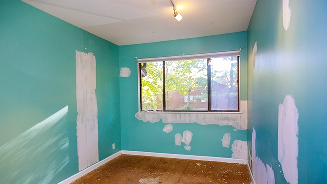 A partially painted teal room with white patches on the walls.