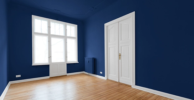 A spacious room with deep blue walls and white window and door.