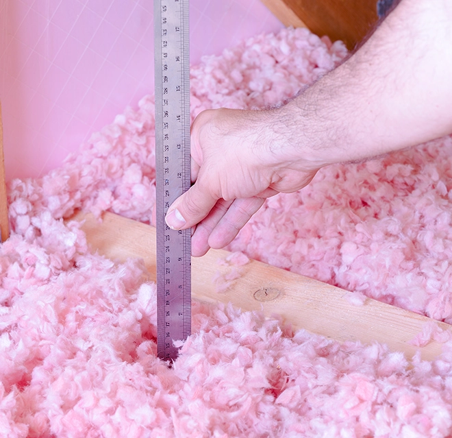 Measuring attic insulation.