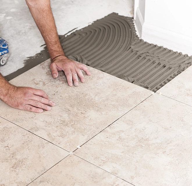 Handyman installing ceramic tiles on a floor.