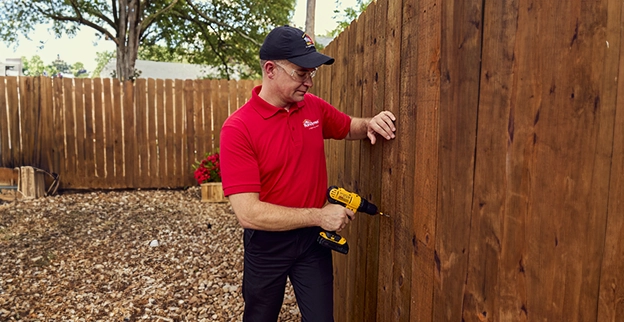 Handyman drilling the wooden wall with machine.