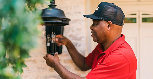 Handyman adjusting the light bulbs in a decorative outdoor lantern.