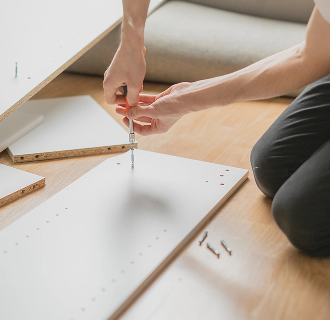 A person using a screwdriver to assemble furniture.