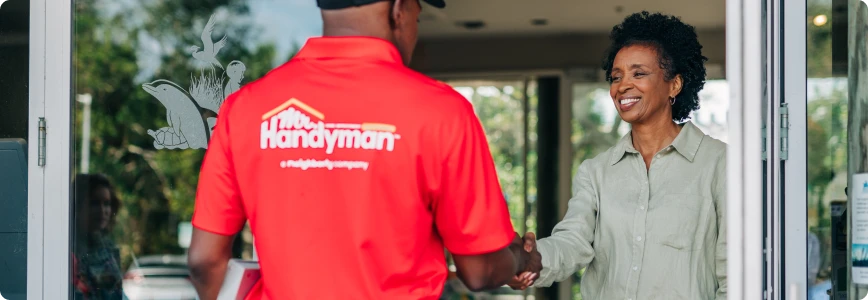 A Mr. Handyman service professional greeting a customer.