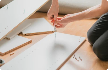 A person assembling flat pack furniture with a screwdriver.