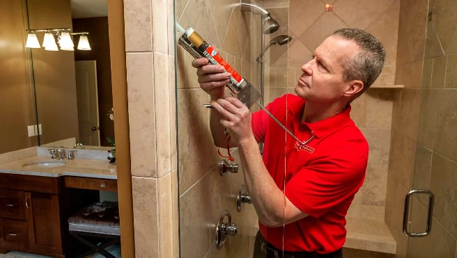 Mr. Handyman caulking tile in bathroom.