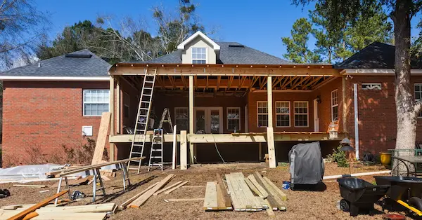 Ongoing exterior home repairs for the back of a single-story house with a raised deck and awning.