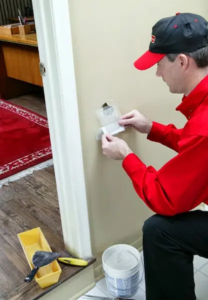 Mr. Handyman, technician repairing drywall damage in Wichita home.