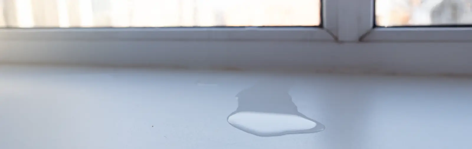 Close-up view showing water pooling on the ledge of a residential window.