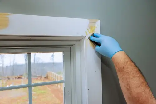 Worker patching holes in window trim.