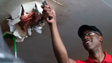 A Mr. Handyman professional repairing a water-damaged ceiling.