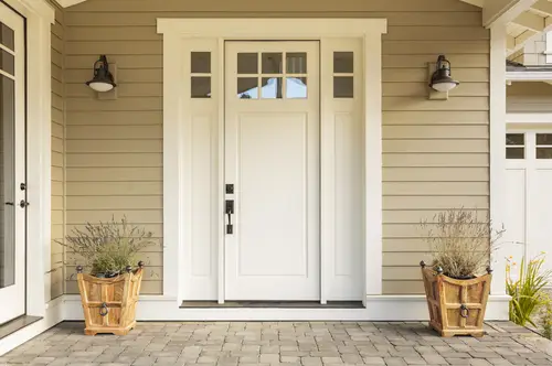 Empty room with yellow walls and a white door A white residential front door with plants on either side.