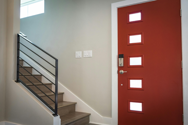 Interior shot of a red door with small square windows next to a staircase.